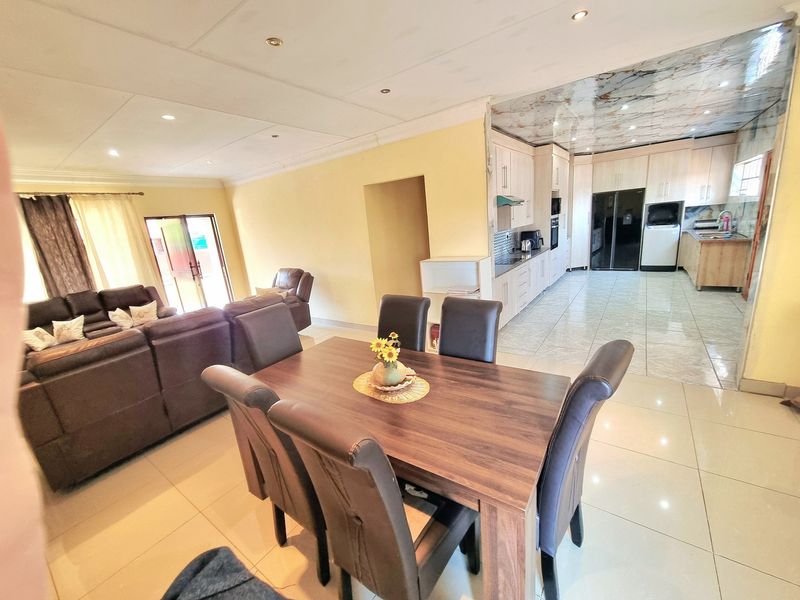 Spacious open-plan living, dining, and kitchen area featuring tiled floors, recessed lighting, and a functional kitchen layout with built-in cabinetry and appliances.