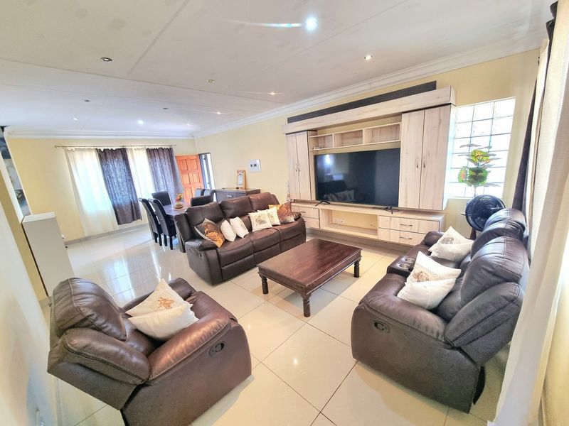 Spacious open-plan living area featuring tiled floors, recessed lighting, and a large built-in entertainment unit with integrated storage.