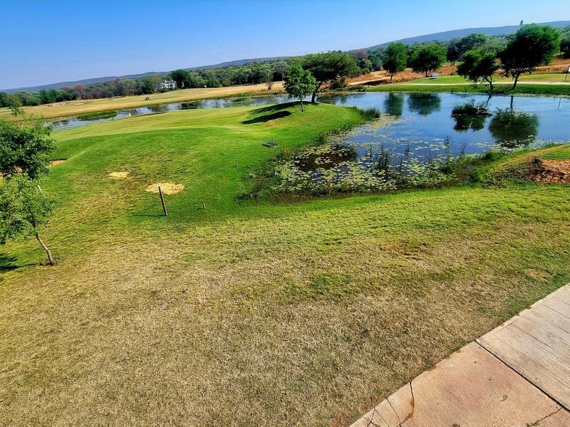 A scenic view of a landscaped golf course featuring a tranquil pond and well-maintained green spaces.