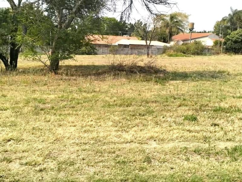 A spacious, level residential vacant land plot featuring established trees and perimeter walling, offering a blank canvas for future development.