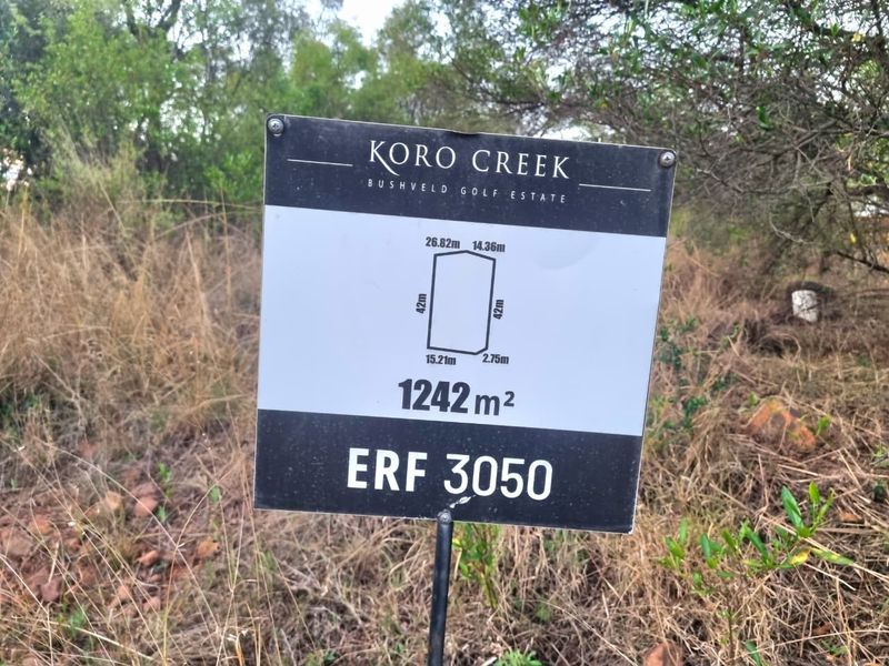 A property signage board displaying the erf number and dimensions for a 1242 square meter residential plot in Koro Creek Bushveld Golf Estate.