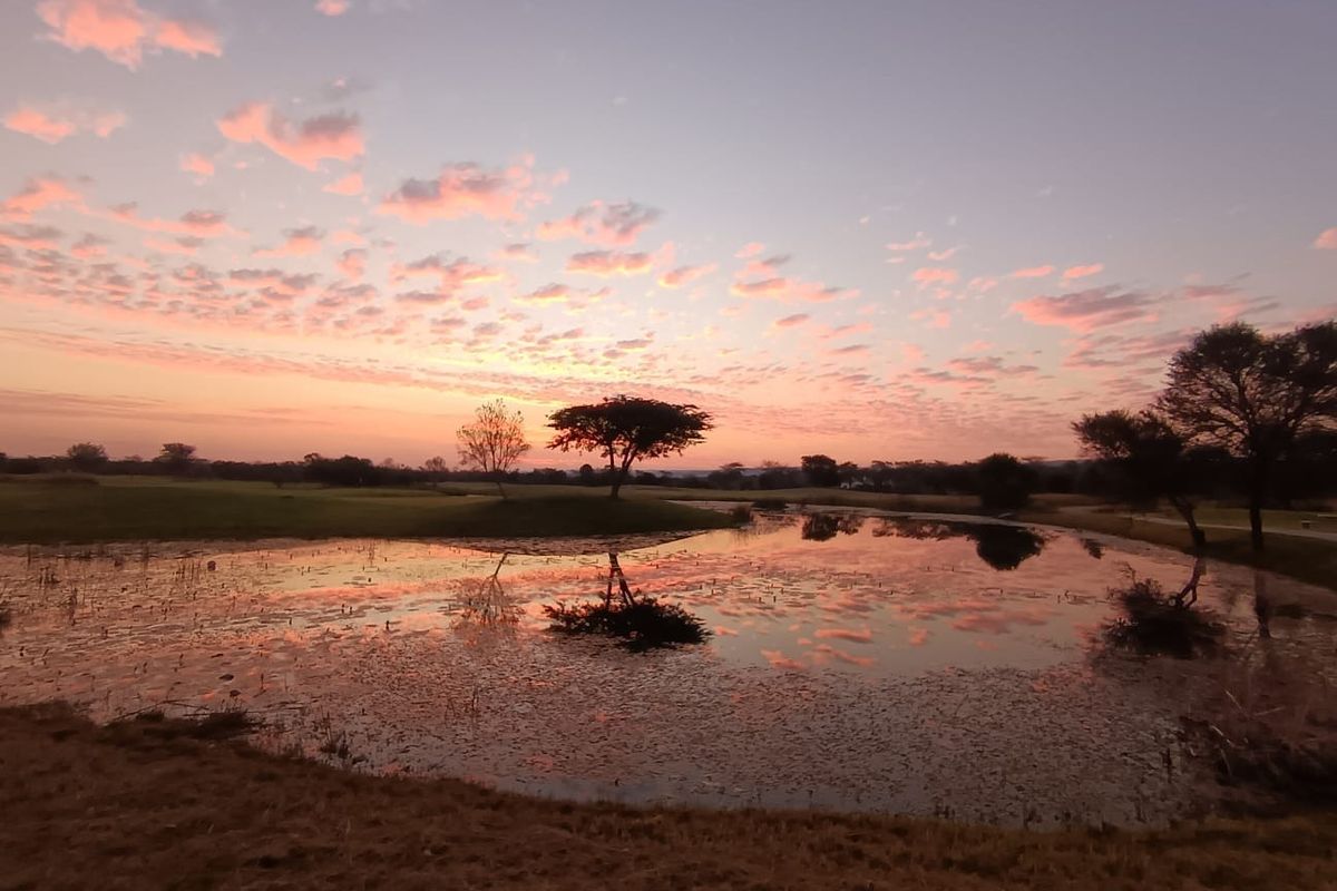 A scenic view of a natural pond and surrounding landscape at sunset, showcasing the tranquil outdoor environment of the vacant land property.