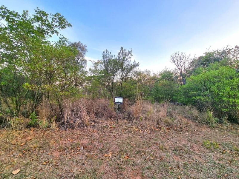 A view of a vacant residential plot featuring natural vegetation and mature trees, suitable for future development.