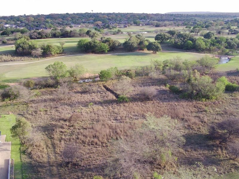 Aerial view of a vacant residential plot featuring natural vegetation, situated adjacent to a golf course.