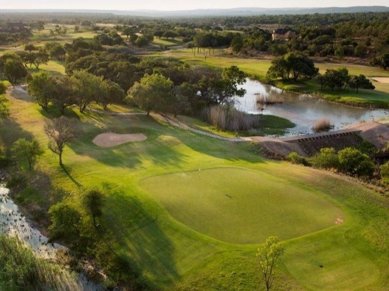 An elevated aerial view showcasing a scenic golf course landscape with a natural pond and lush green surroundings.