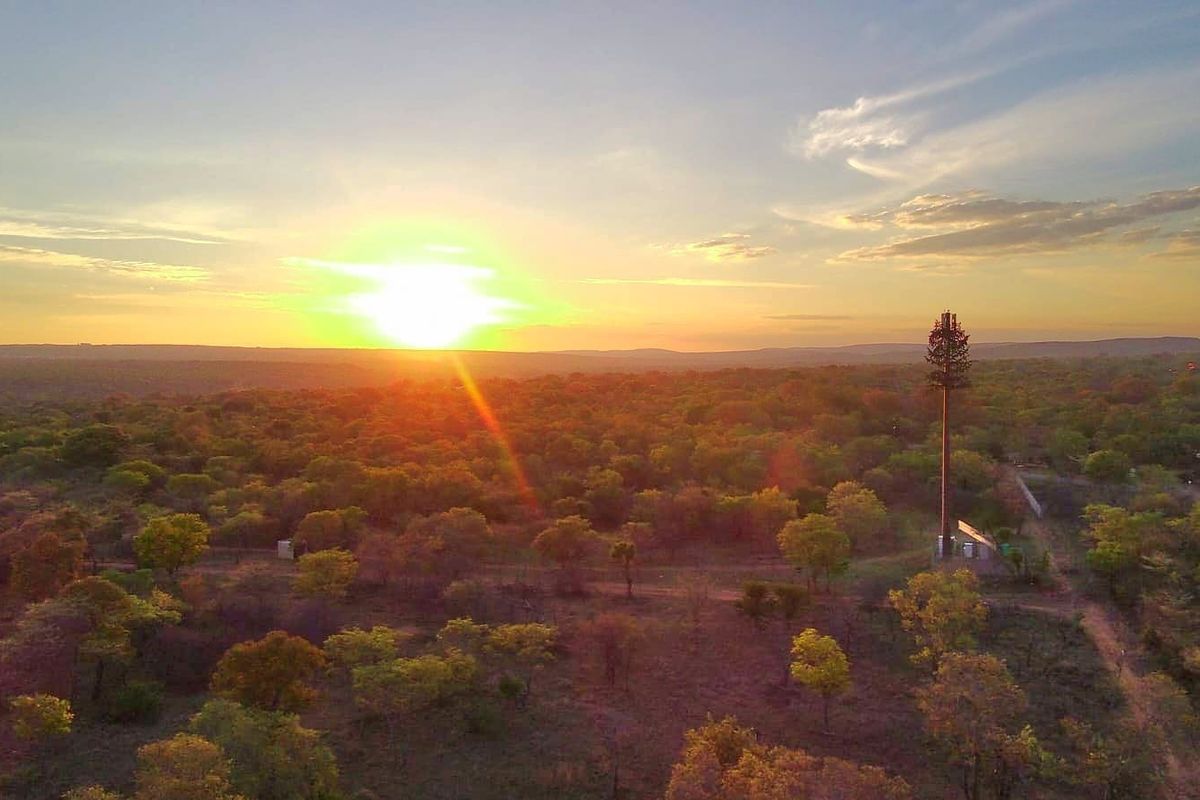 An aerial view of a rural landscape featuring a telecommunications tower at sunset.