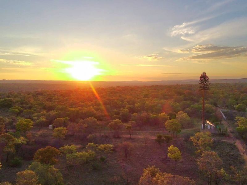 An aerial view of a rural landscape featuring a telecommunications tower at sunset.