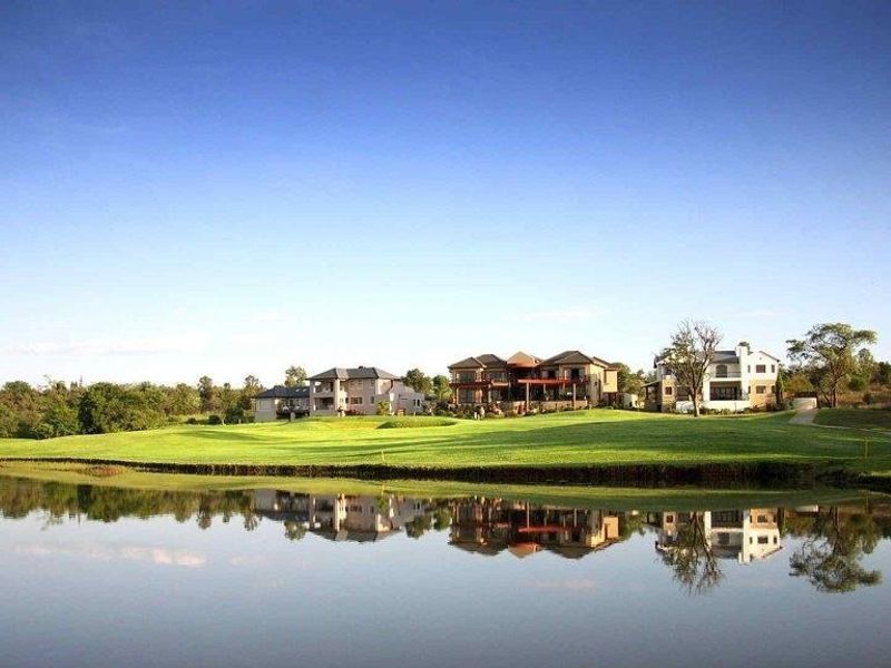 A scenic view of luxury residential properties situated along a golf course fairway and a tranquil lake.