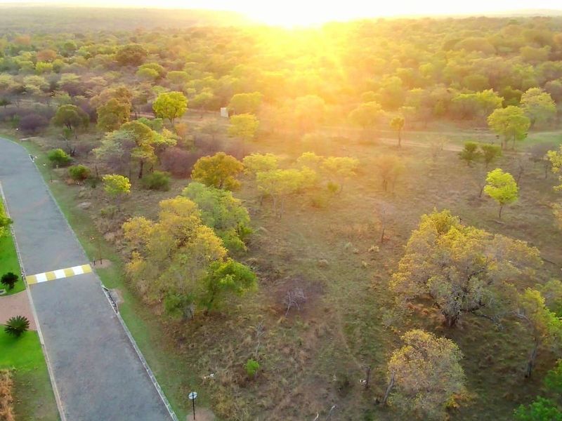 An aerial view of the property surroundings featuring a paved road and natural landscape at sunset.