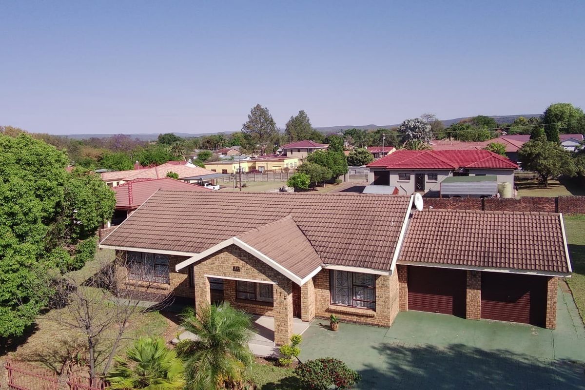 Aerial view of a single-story brick house featuring a tiled roof, double garage, and a spacious front yard in a residential neighborhood.