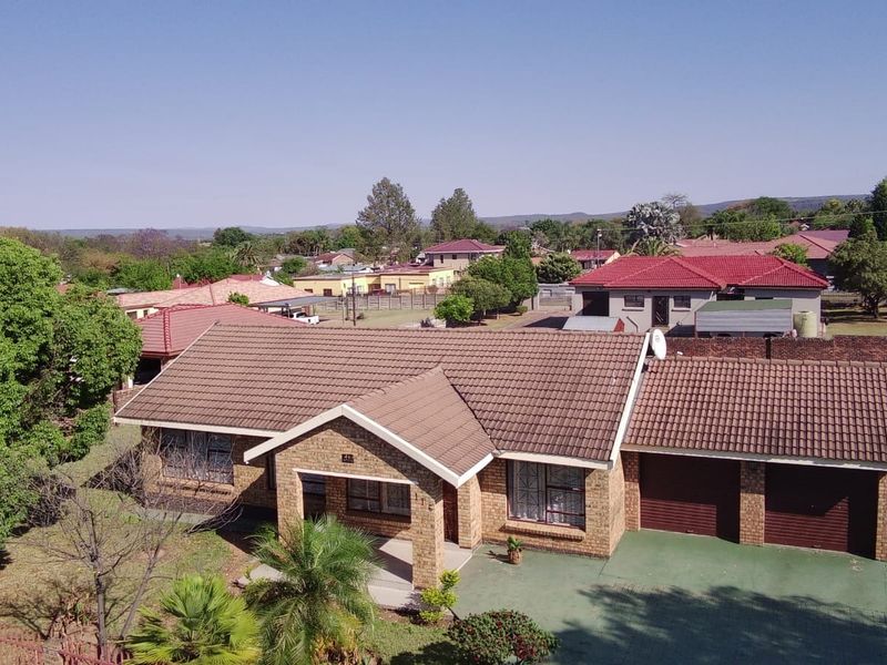 Aerial view of a single-story brick house featuring a tiled roof, double garage, and a spacious front yard in a residential neighborhood.