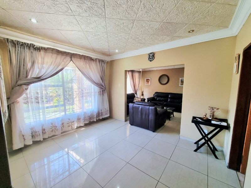 Spacious living area featuring tiled flooring, a textured ceiling with recessed lighting, and large windows allowing for ample natural light.