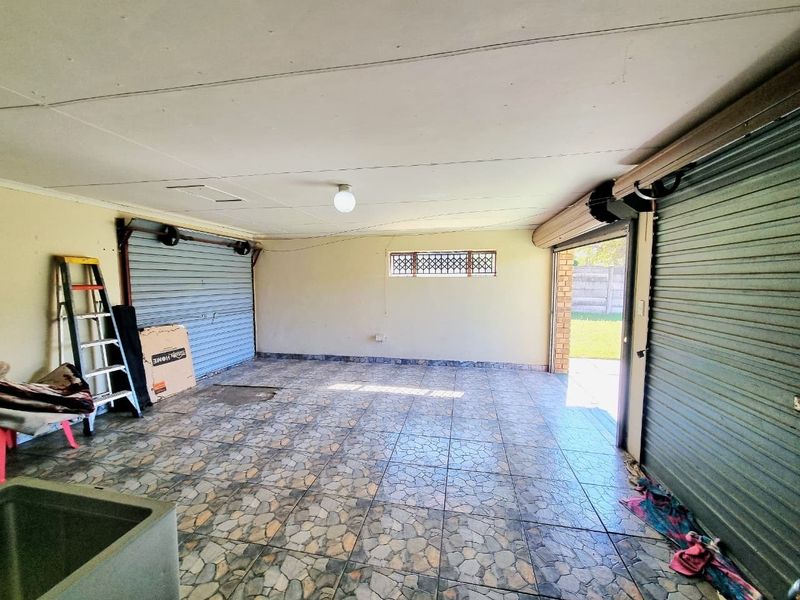 Spacious double garage featuring tiled flooring, roller shutter doors, and direct access to the rear garden area.