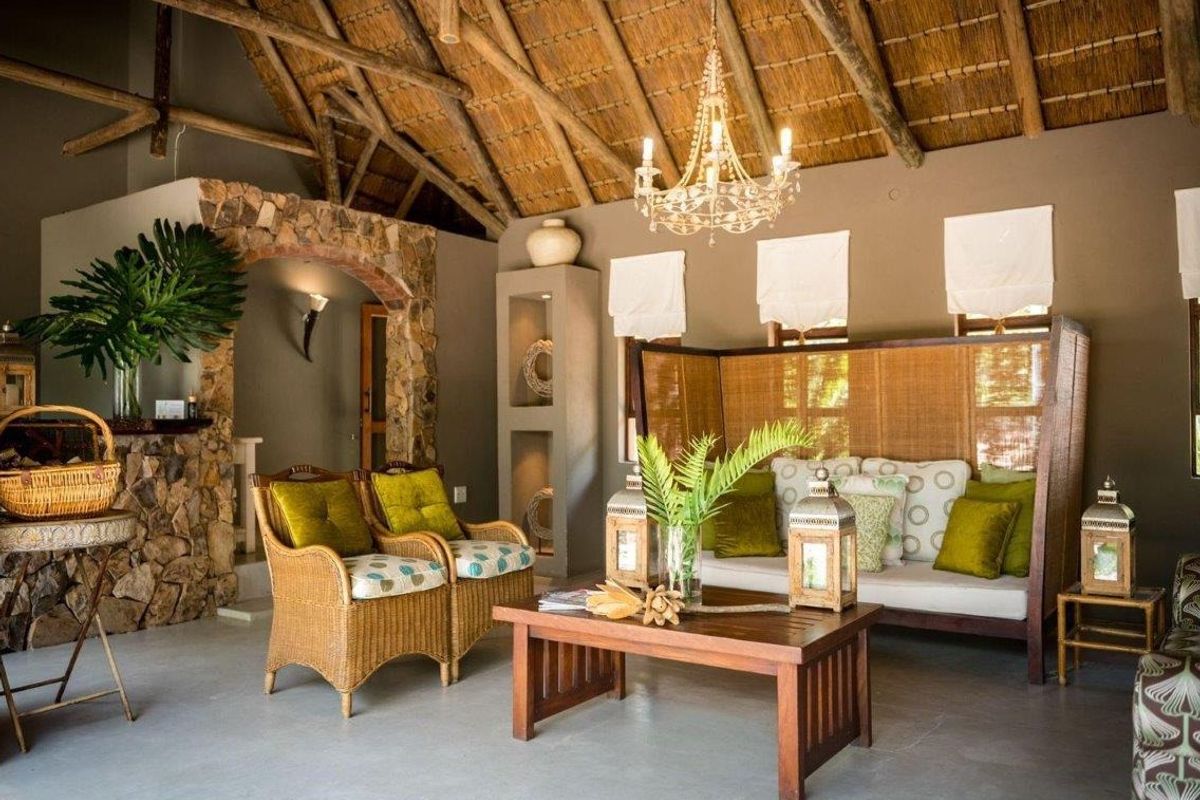 A spacious living area featuring a high thatched roof with exposed timber rafters, a rustic stone archway, and built-in wall niches.