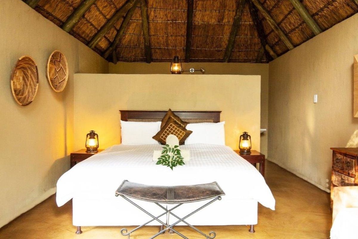 A rustic bedroom featuring a traditional thatched roof with exposed timber rafters and a central partition wall, creating a warm and authentic farm-style atmosphere.