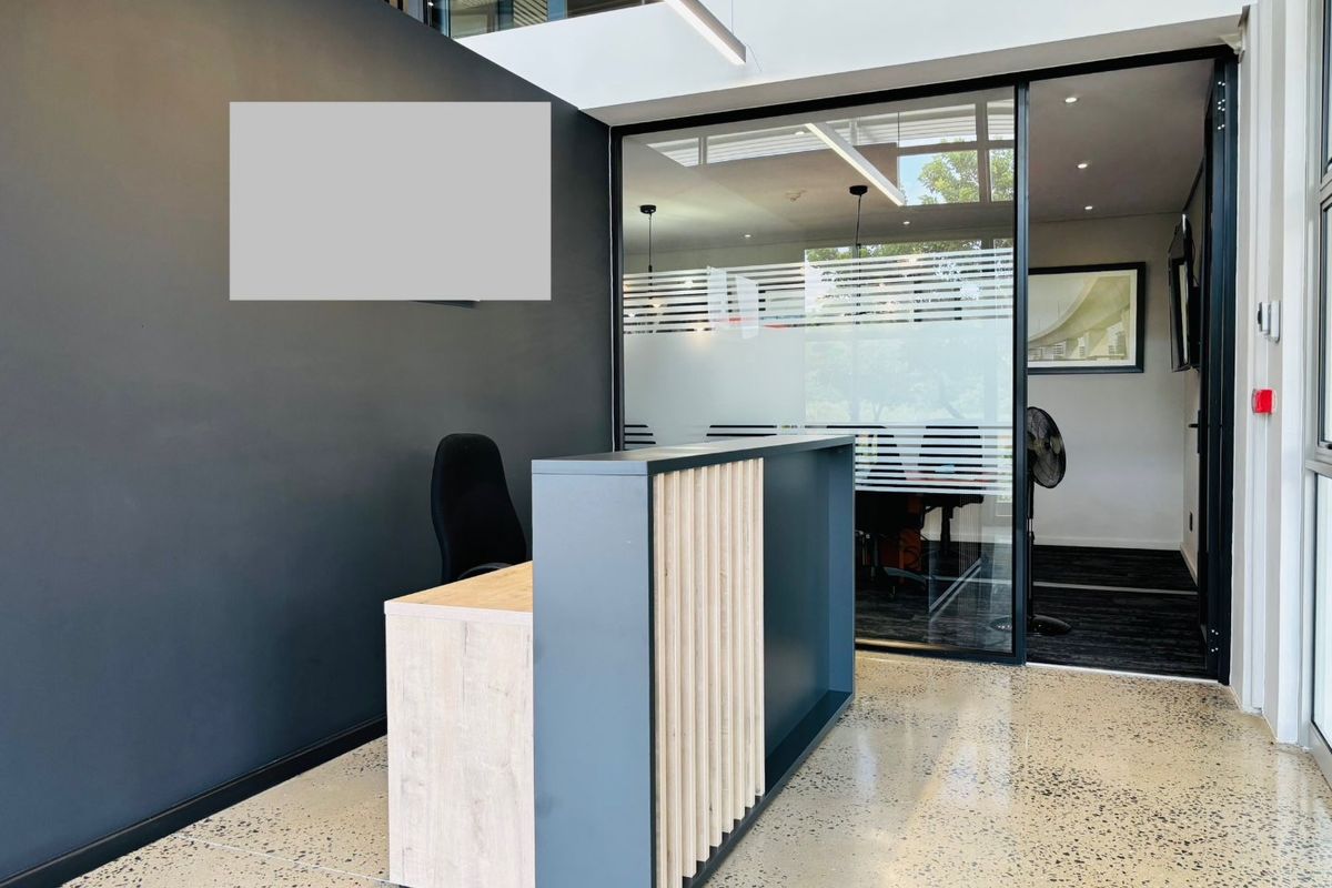 Modern commercial reception area featuring a contemporary desk, polished concrete floors, and a glass-partitioned office space with clean, professional finishes.