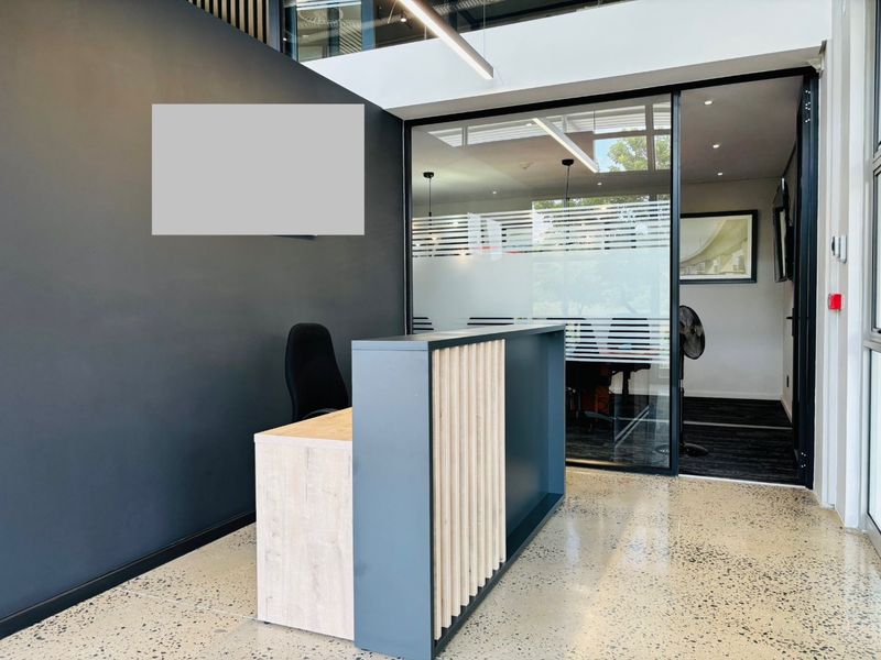 Modern commercial reception area featuring a contemporary desk, polished concrete floors, and a glass-partitioned office space with clean, professional finishes.