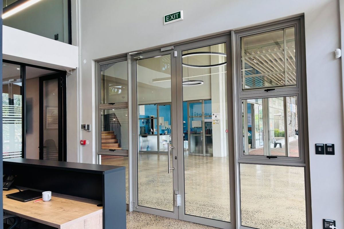 Modern commercial entry area featuring polished concrete floors and large aluminium-framed glass doors providing clear visibility into the office space.