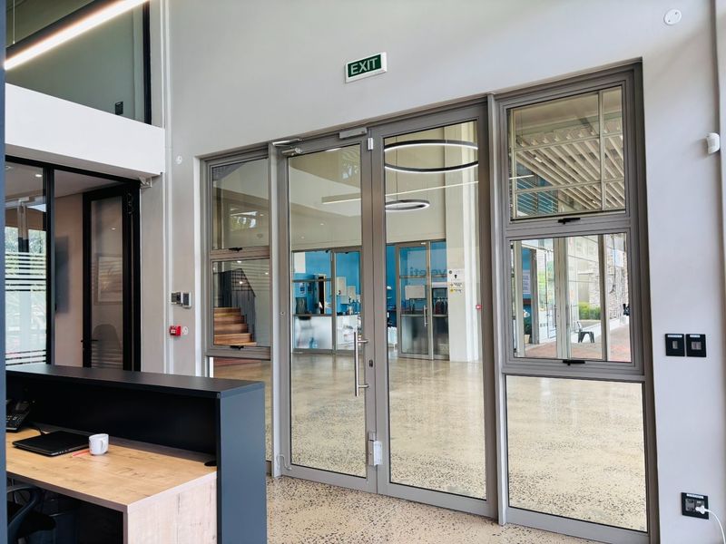 Modern commercial entry area featuring polished concrete floors and large aluminium-framed glass doors providing clear visibility into the office space.