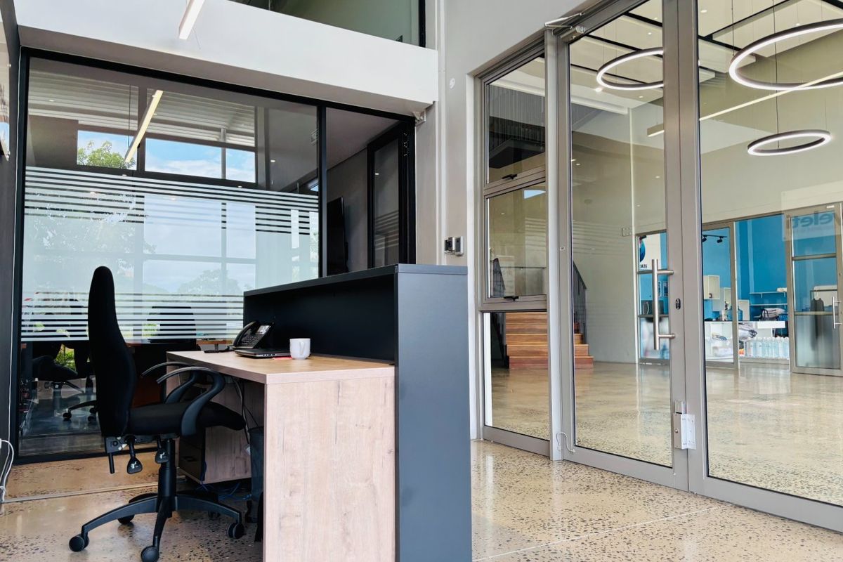 Modern commercial office space featuring polished concrete floors, glass partitioning, and contemporary lighting fixtures, creating a professional and bright work environment.