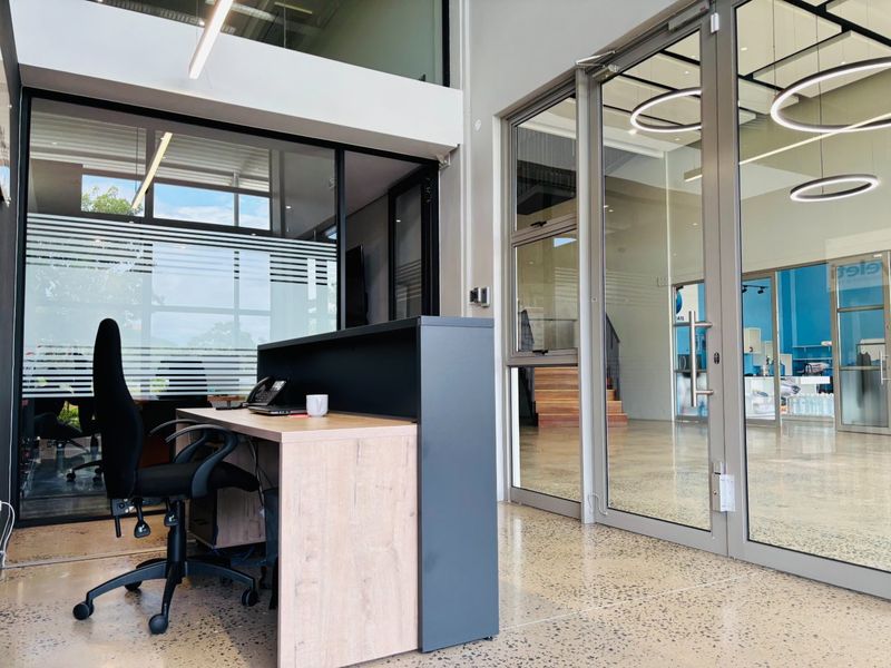 Modern commercial office space featuring polished concrete floors, glass partitioning, and contemporary lighting fixtures, creating a professional and bright work environment.
