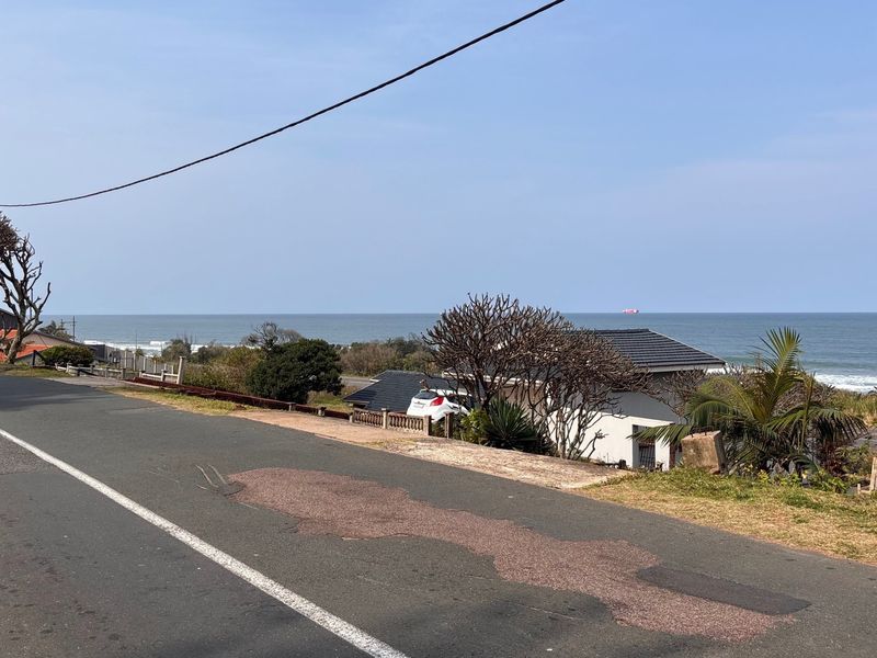 A scenic view of the ocean and coastal landscape from the roadside, showcasing the property's prime location and outlook.