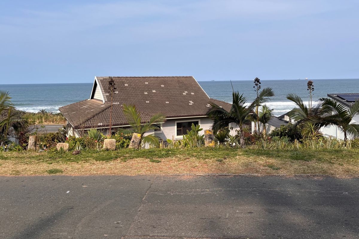 Rear view of a coastal property featuring a tiled roof with visible missing tiles, set against an ocean backdrop.