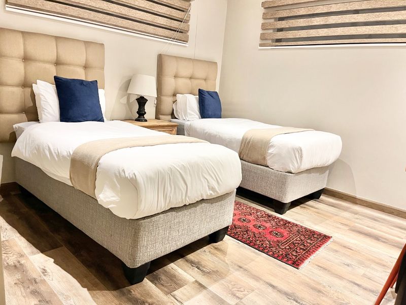 A well-maintained bedroom featuring durable laminate flooring and modern roller blinds, providing a clean and comfortable living space.