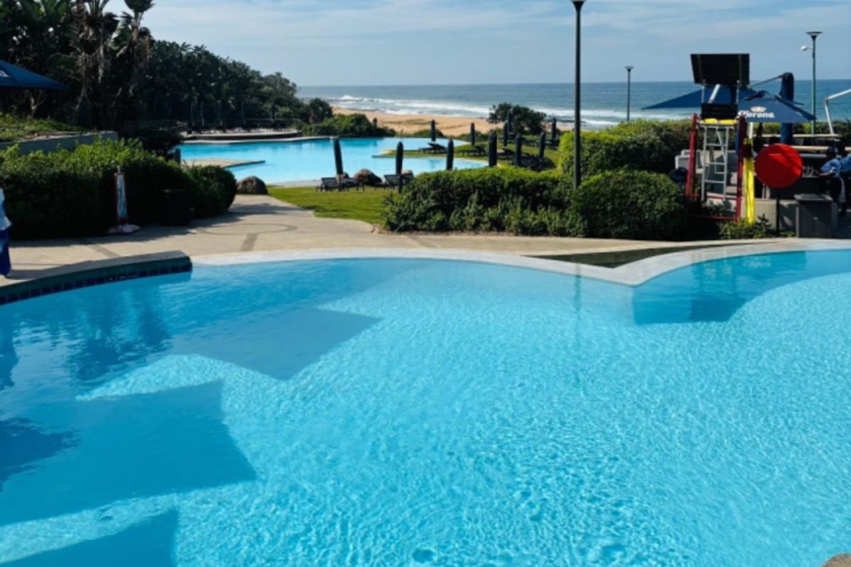 A well-maintained outdoor swimming pool area featuring landscaped gardens and direct views of the nearby coastline.