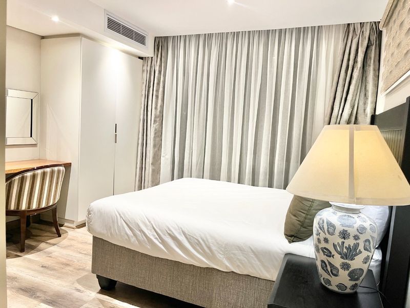 A well-maintained bedroom featuring built-in cabinetry, recessed lighting, ducted air conditioning, and modern laminate flooring.