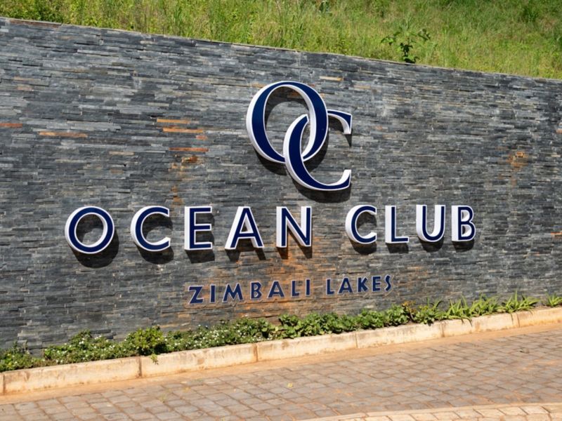 A well-maintained stone feature wall displaying the Ocean Club Zimbali Lakes signage at the entrance of the property.