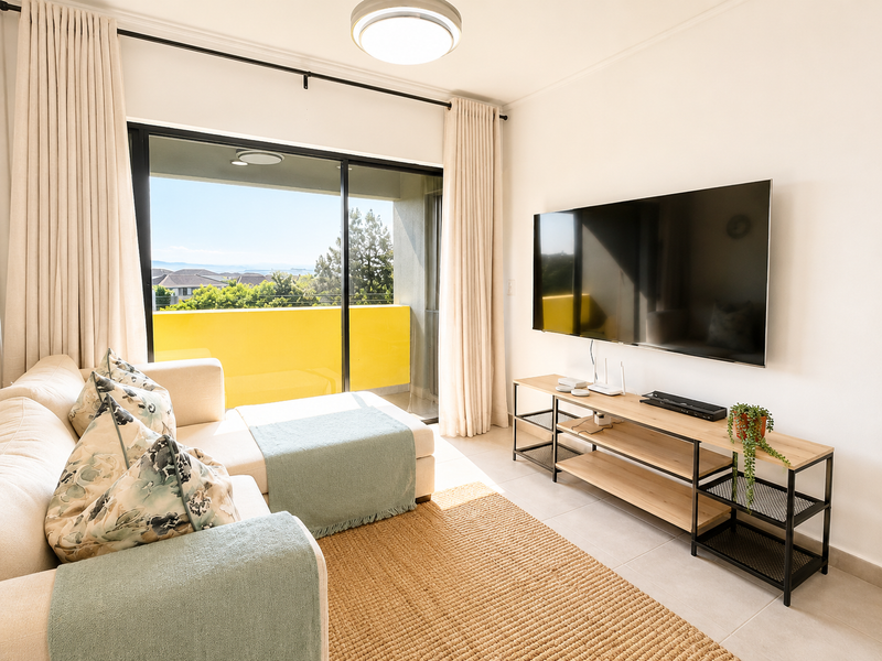 A bright living room featuring tiled flooring, a large sliding glass door leading to a balcony, and neutral wall finishes.