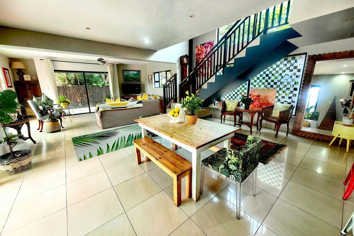 Spacious open-plan living and dining area featuring large format floor tiles, a modern staircase with metal balustrade, and sliding doors leading to the outdoors.