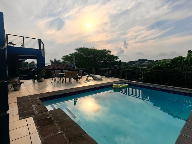 Outdoor pool area featuring a tiled deck, metal balustrades, and a raised balcony level, offering an elevated space for relaxation and entertainment.