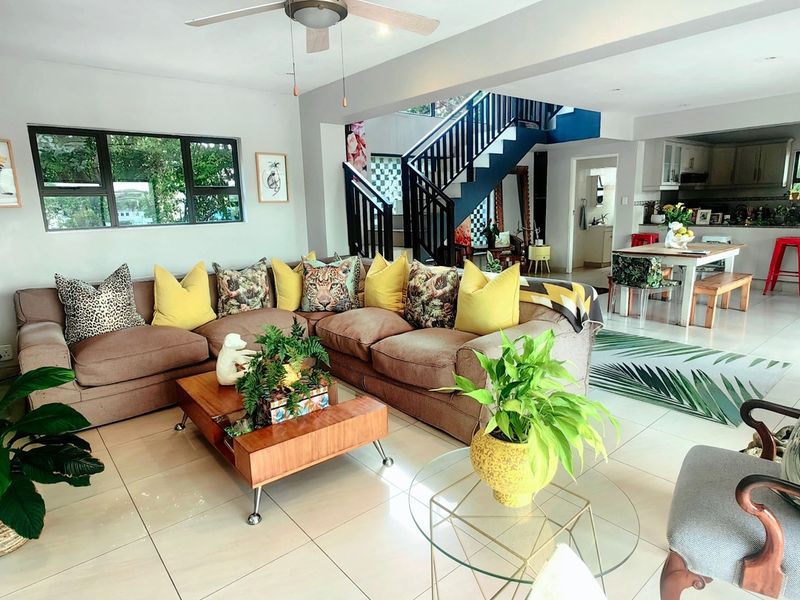 Spacious open-plan living area featuring tiled floors, a central staircase, and a connected kitchen, creating a bright and functional family living space.