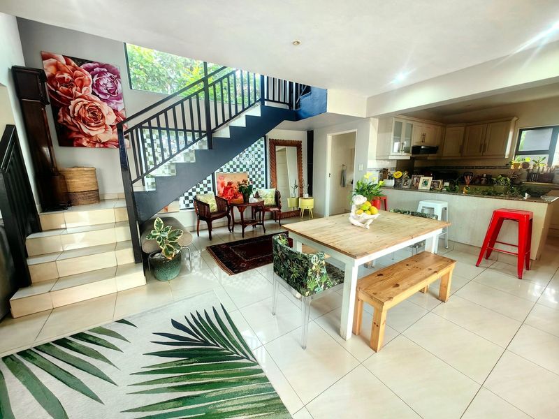 Spacious open-plan living and dining area featuring tiled floors, a modern staircase, and an integrated kitchen with granite countertops.