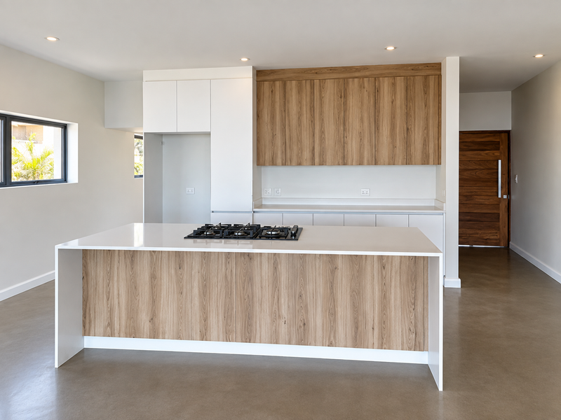 Modern kitchen featuring a central island with a gas hob, sleek wood-grain cabinetry, stone countertops, and polished concrete flooring in an open-plan layout.