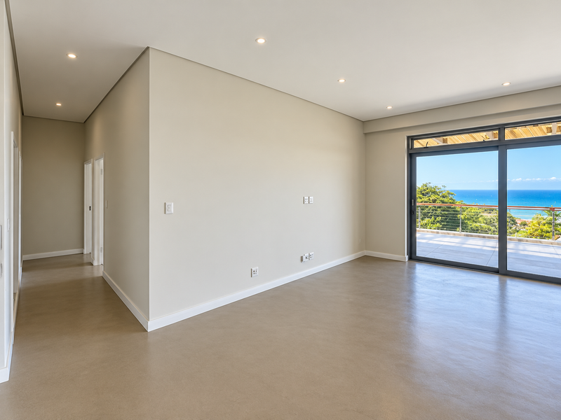 Spacious, modern living area featuring neutral finishes, recessed lighting, and large sliding glass doors opening to a balcony with scenic ocean views.