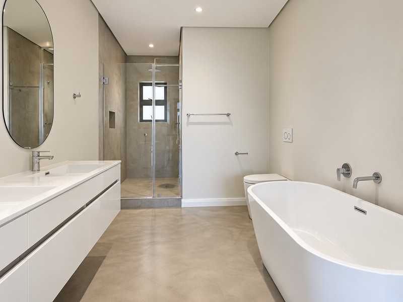 Modern bathroom featuring a double vanity, glass-enclosed shower with recessed niche, and a sleek freestanding bathtub with wall-mounted fixtures.