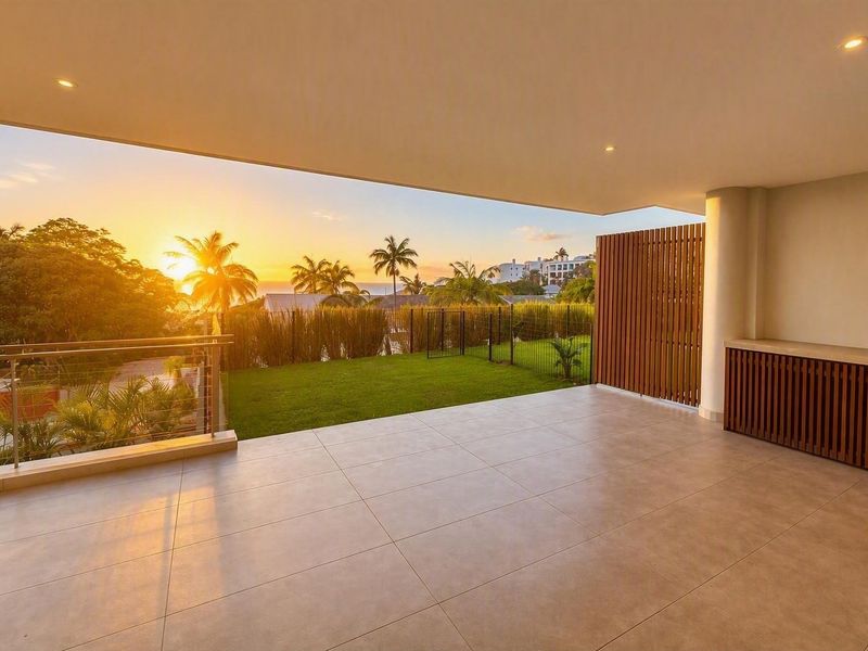 Spacious covered balcony featuring modern tiled flooring, recessed lighting, and a timber privacy screen, offering scenic sunset views over the garden.