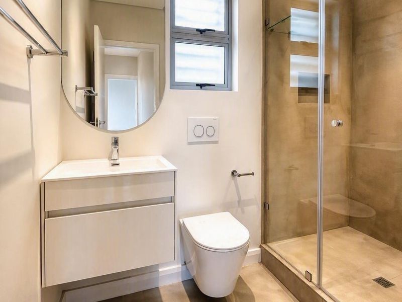 Modern bathroom featuring a wall-mounted vanity, wall-hung toilet with concealed cistern, and a spacious walk-in shower with glass enclosure.