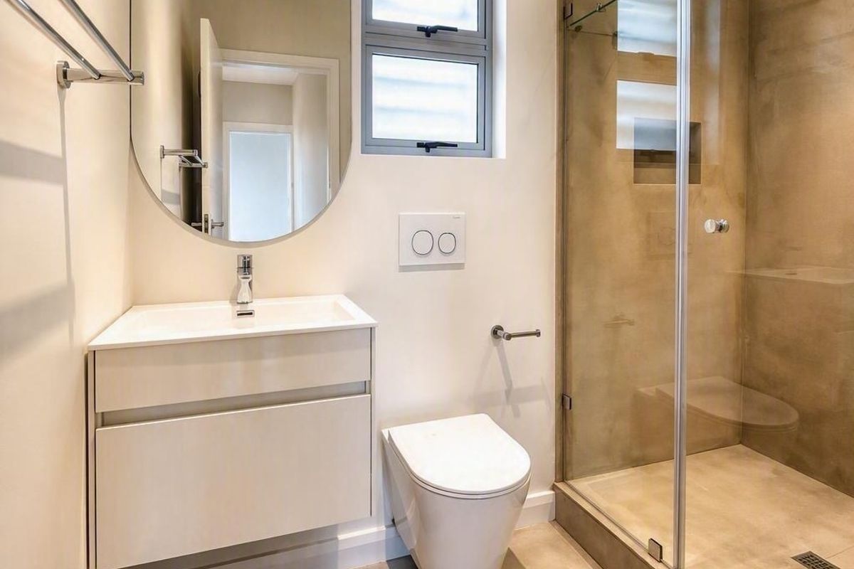 Modern bathroom featuring a wall-mounted vanity, wall-hung toilet with concealed cistern, and a spacious walk-in shower with glass enclosure.
