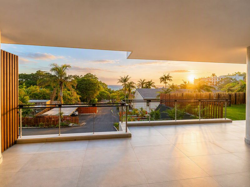 Spacious covered balcony featuring modern tiled flooring, sleek stainless steel balustrades, and expansive sunset views over the surrounding landscape.