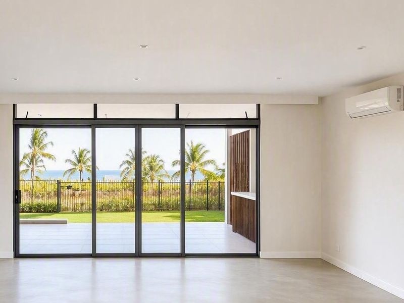 Bright and spacious living area featuring large sliding glass doors that open to a patio with scenic views, complemented by modern air conditioning.