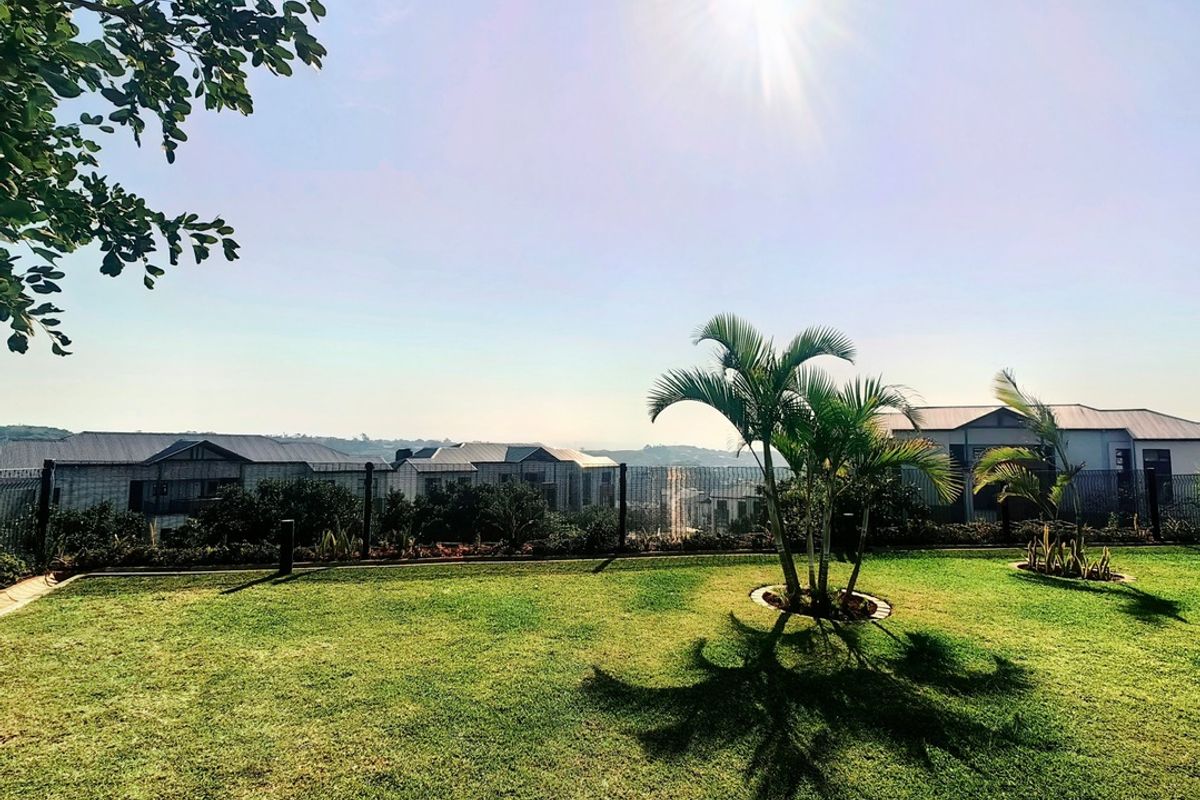 A well-maintained rear garden featuring a manicured lawn and perimeter fencing, offering an open outlook over the surrounding residential area.