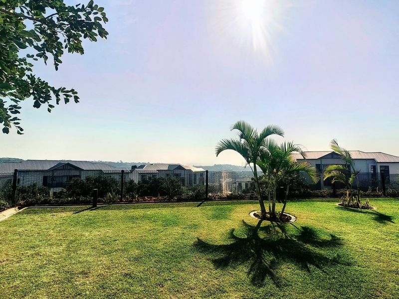 A well-maintained rear garden featuring a manicured lawn and perimeter fencing, offering an open outlook over the surrounding residential area.