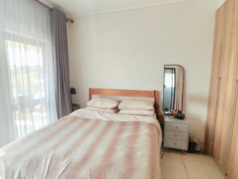 A well-lit bedroom featuring tiled flooring, a built-in wardrobe, a ceiling fan, and a sliding glass door providing access to an outdoor area.
