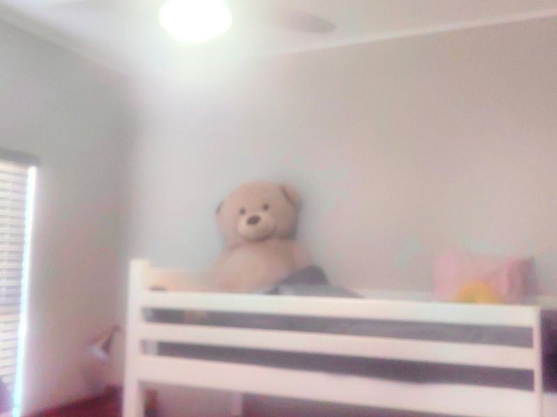 A bedroom featuring a ceiling fan and venetian blinds, captured in a low-quality, blurry photograph.