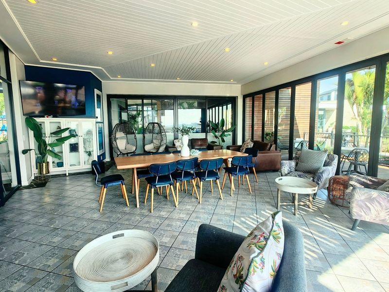 Spacious open-plan living and dining area featuring tiled floors, a decorative tongue and groove ceiling, and expansive sliding glass doors leading to the outdoors.