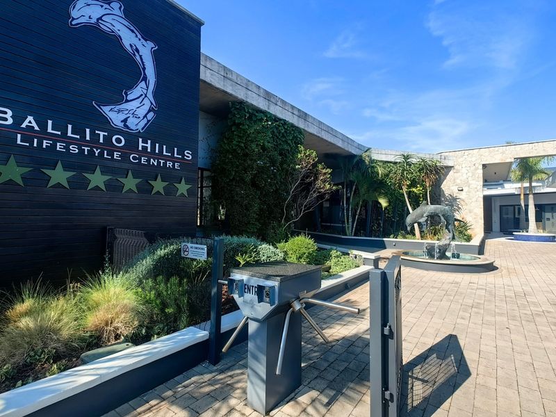 The entrance to the Ballito Hills Lifestyle Centre featuring a secure turnstile, paved walkway, and a decorative water feature.